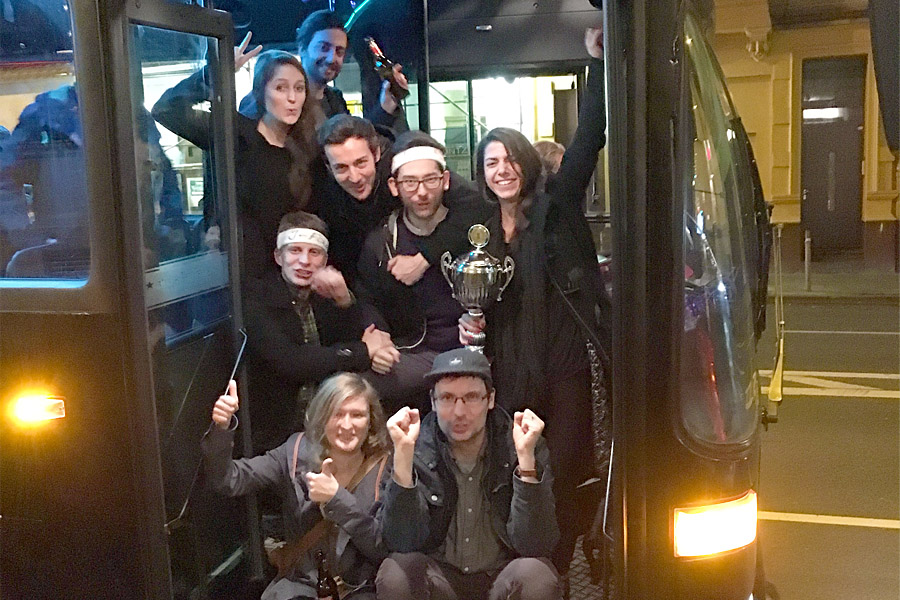 Foto Bus Tür auf Team dreiform schaut mit Pokal in der Hand raus