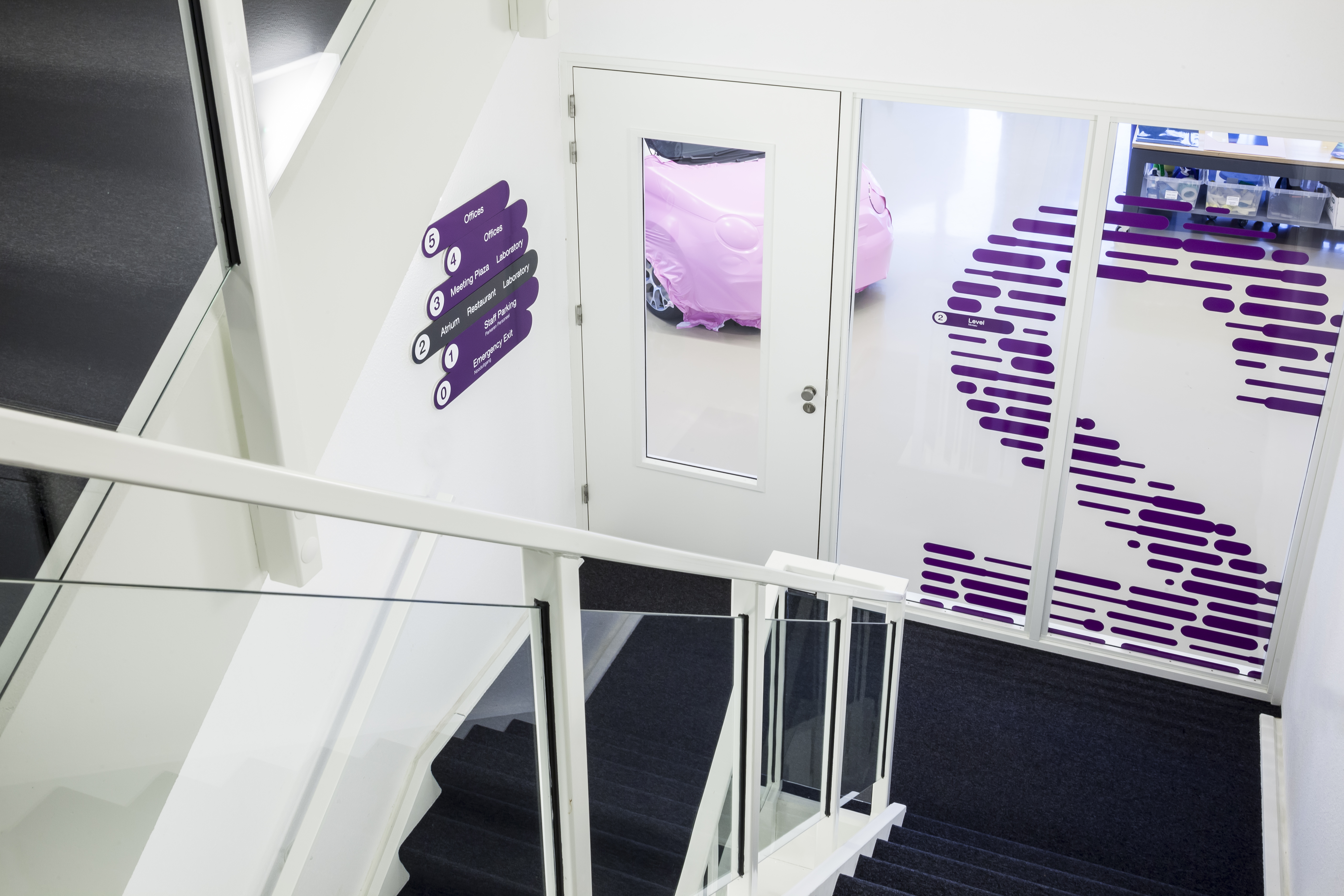 Treppenhaus 2 OG Nummer 2 aus violetten Linien auf Glaswand und Wegweiser