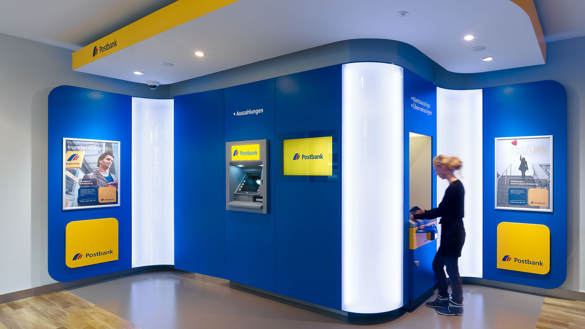 Interior of the branch with illuminated interior. Customer is at the ATM