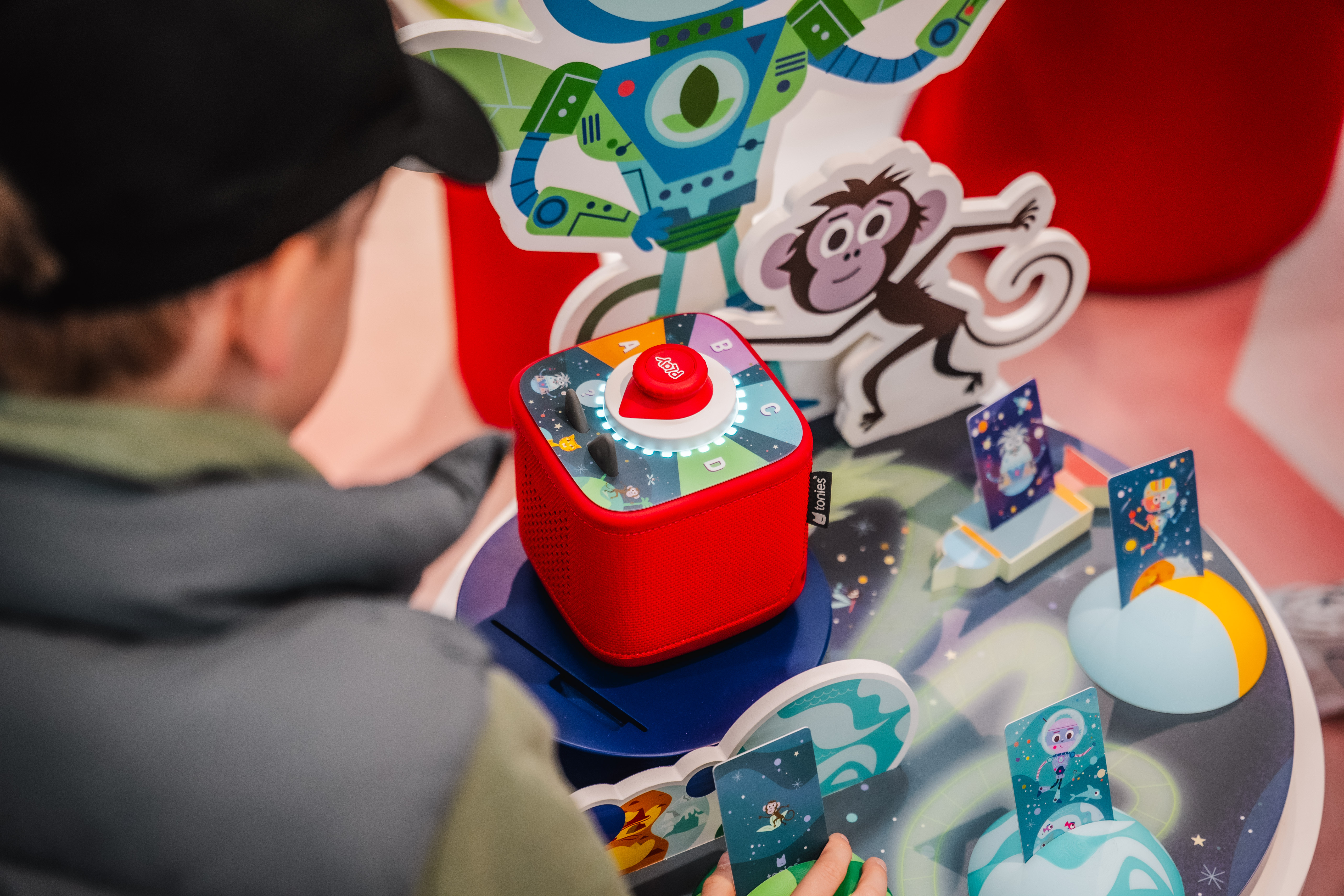 Glance over the shoulder at a boy who is currently interacting with a Toniebox 2.