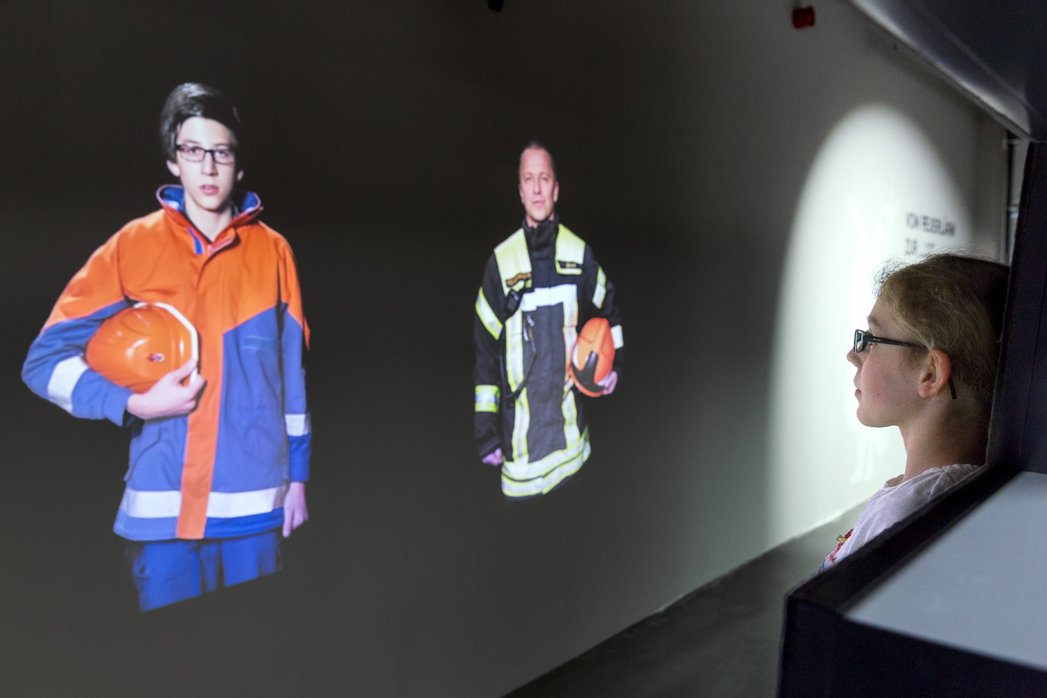 Child looks at projection of a young member of the volunteer fire brigade