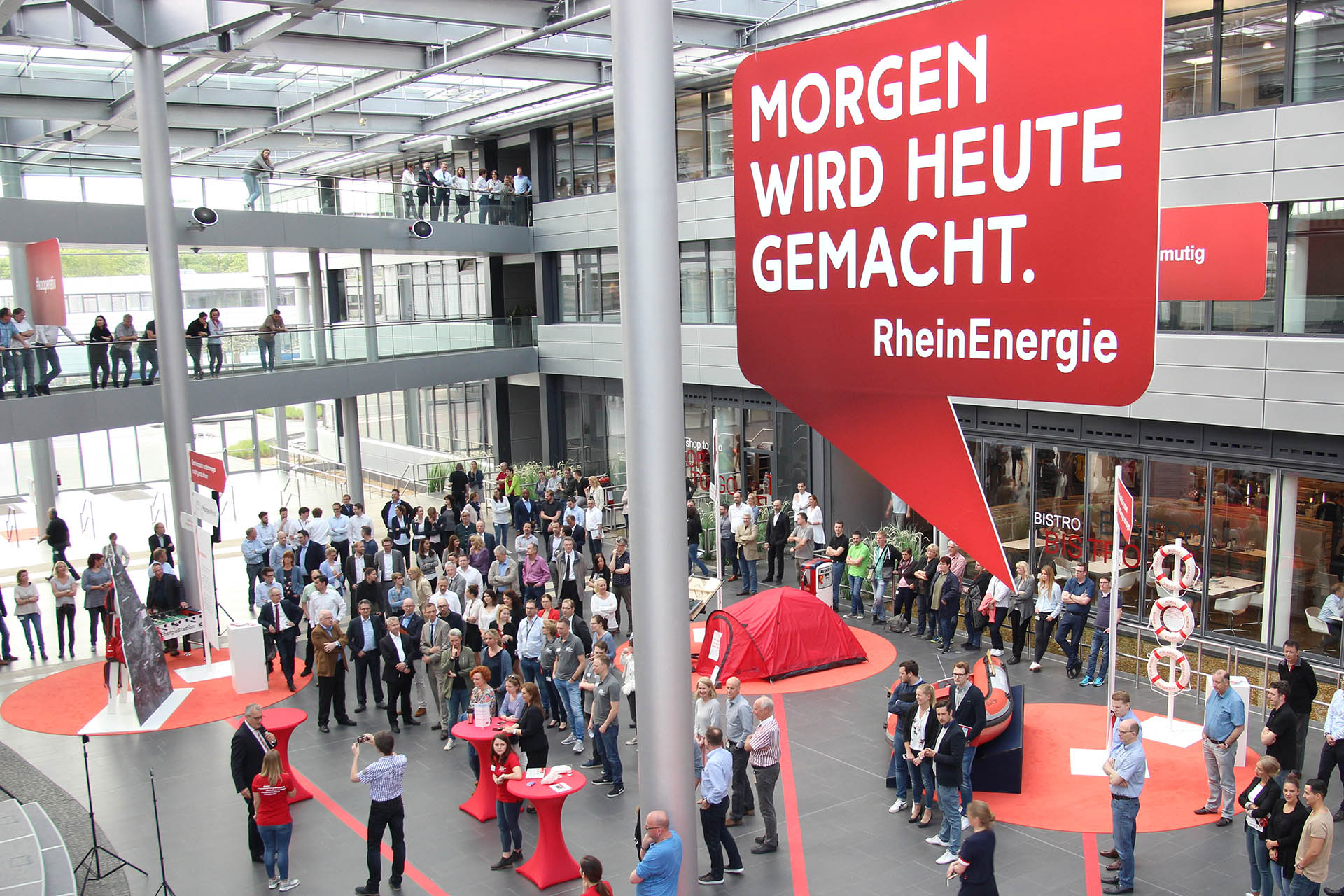 View of exhibition with large motto sign hanging from the ceiling